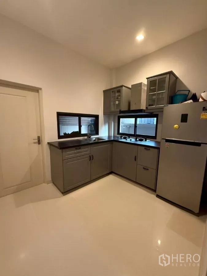 Detached House for rent or sale in Bang Phli, Samut Prakan - Separate Thai kitchen with L‑shaped grey cabinets, gas hob and refrigerator.