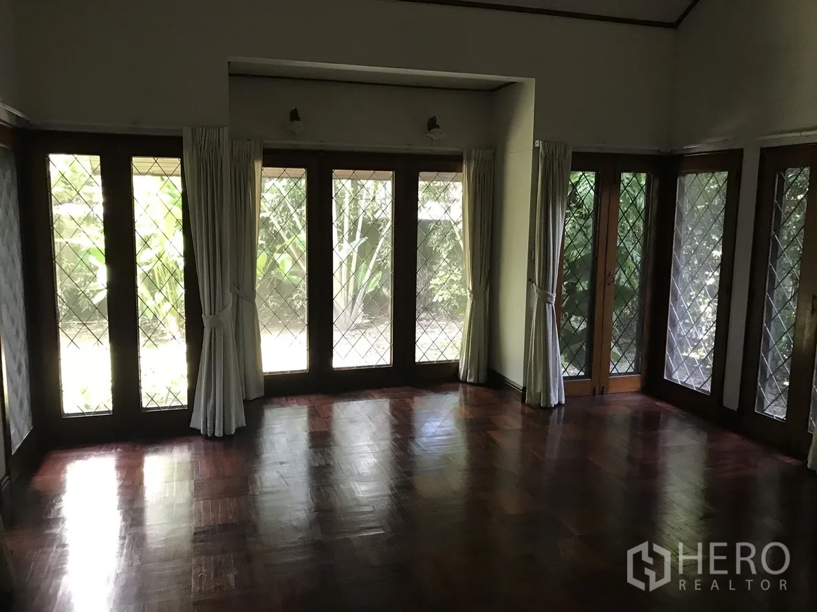 独立式住宅 出租在Khlong Toei, Bangkok - 采光良好的房间，落地窗围合，花园景观与木地板。