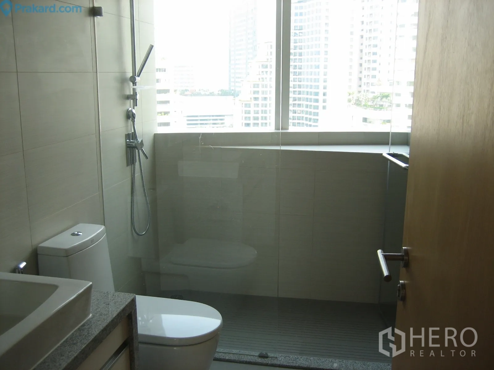Condominium for rent in Khlong Toei, Bangkok - Modern bathroom with glass-enclosed shower, window and contemporary fixtures.