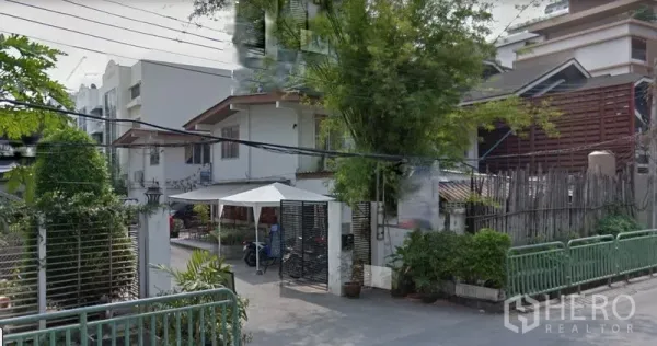 Retail Space for rent in Watthana, Bangkok - Street view of a low-rise retail building with gated entrance, greenery and neighboring homes in the Sukhumvit 31 area.