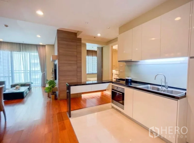 Condominium for rent in Khlong Toei, Bangkok - Sleek L-shaped kitchen with glossy cabinets, under-cabinet lighting and a peninsula counter.