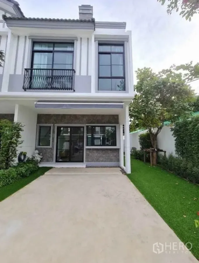 Townhouse for rent in Bang Phli, Samut Prakan - Two-storey townhouse facade with driveway, big windows and landscaped garden.
