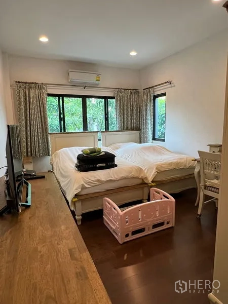 Detached House for sale in Bang Kapi, Bangkok - Airy bedroom with large windows, twin-bed layout and warm wood flooring.