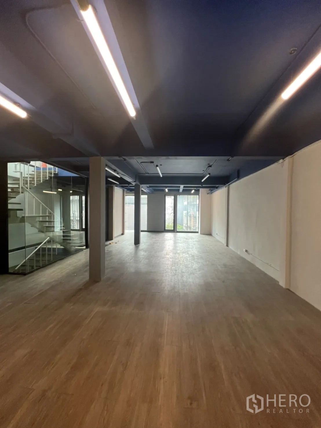 办公空间 出租在Watthana, Bangkok - 纵深型办公布局，面向整面高窗与玻璃楼梯核心。