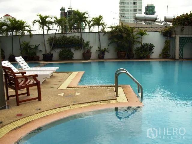 公寓 出租在Watthana, Bangkok - 公寓室外游泳池，设躺椅与热带植物。