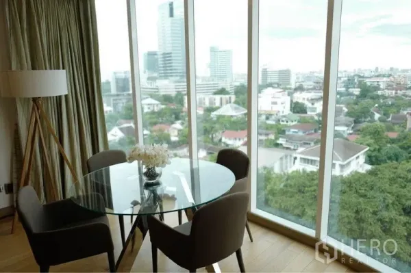 Condominium for rent or sale in Phaya Thai, Bangkok - Dining nook with a round glass table beside floor-to-ceiling windows offering panoramic city skyline views.