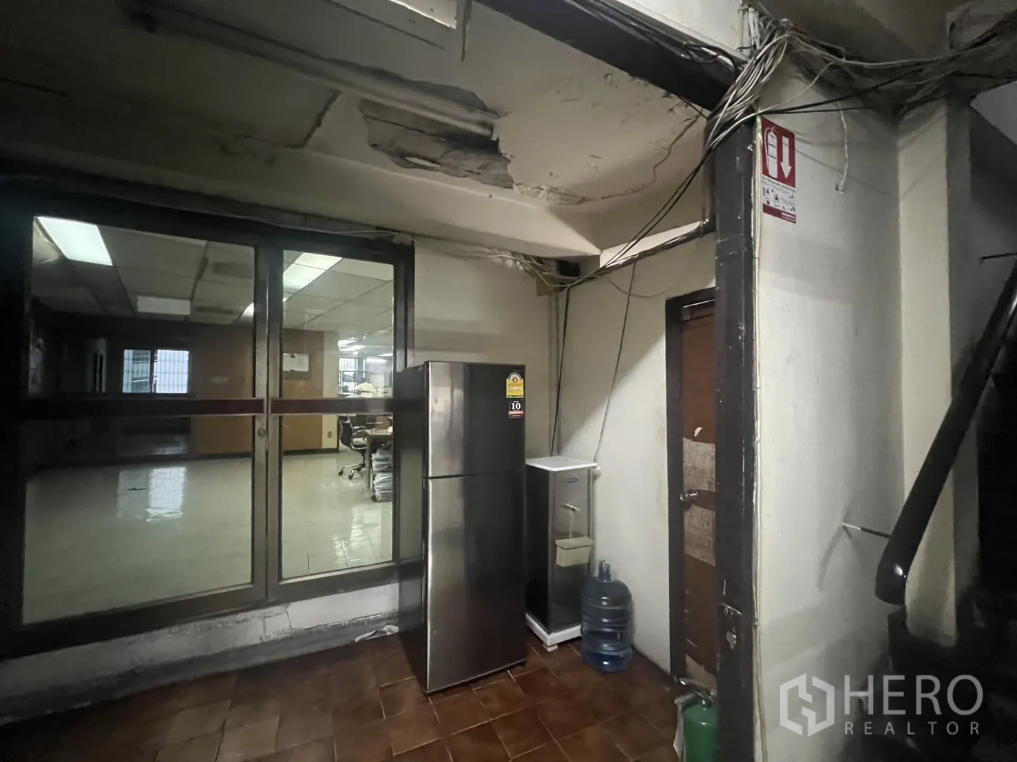 店屋 出租 - 后部服务区域，玻璃门、冰箱与外露天花。