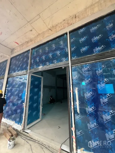 Retail Space for rent in Khlong Toei, Bangkok - Shell-and-core retail unit with floor-to-ceiling glass storefront under installation.