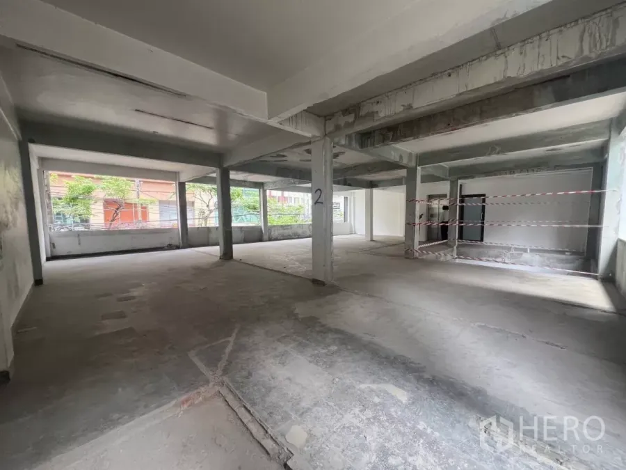 Retail Space for rent in Bang Rak, Bangkok - Open-plan second-floor retail shell with concrete floors, wide columns, and large street-facing windows allowing natural light.