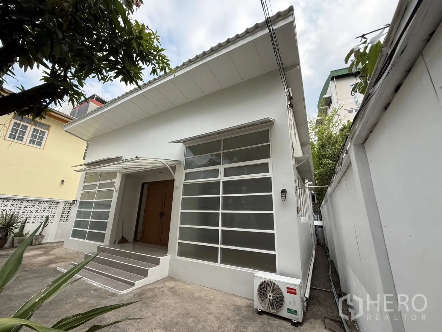 独栋房屋 for rent in Khlong Toei, Bangkok - 房屋侧面视角，入口台阶与室外空调机组可见。