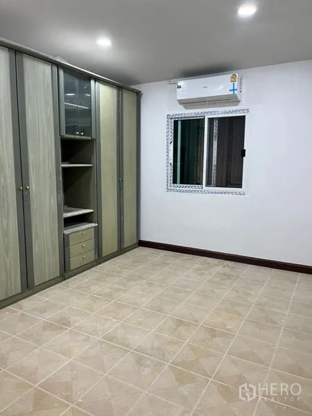 Townhouse for rent in Din Daeng, Bangkok - Bedroom with built-in wardrobes, air conditioning, and a sliding window.