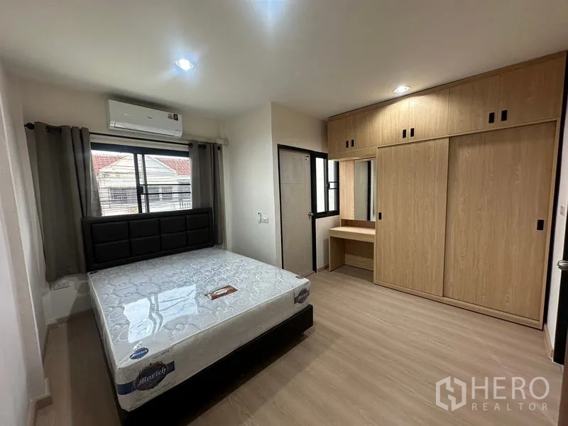Townhouse for rent or sale in Phra Khanong, Bangkok - Bedroom with bed, built-in wardrobe and dressing table under air-con.
