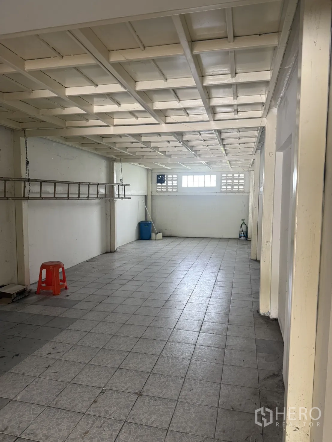 Shophouse for rent in Pak Kret, Nonthaburi - Long rear section with grid ceiling, high window, and tiled floor.