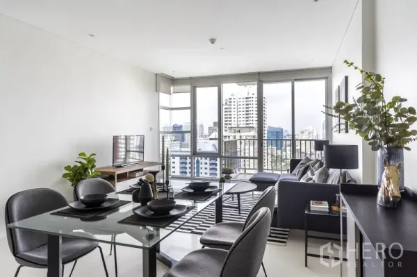 Condominium for rent in Watthana, Bangkok - Glass-top dining table set next to full-height windows with skyline outlook.