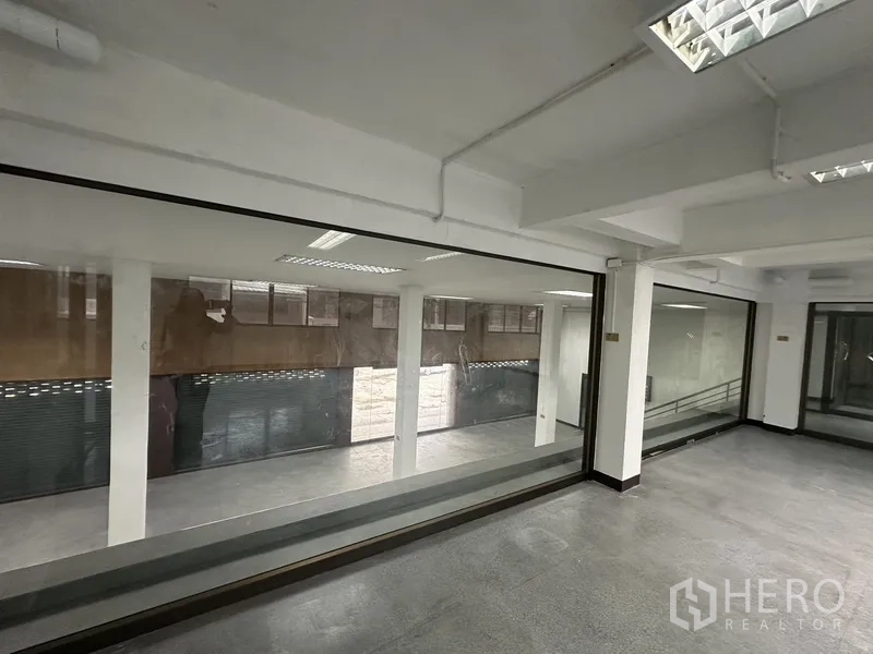 办公空间 出租在Khlong Toei, Bangkok - 室内观景窗俯瞰下层空间，可见立柱与卷闸门