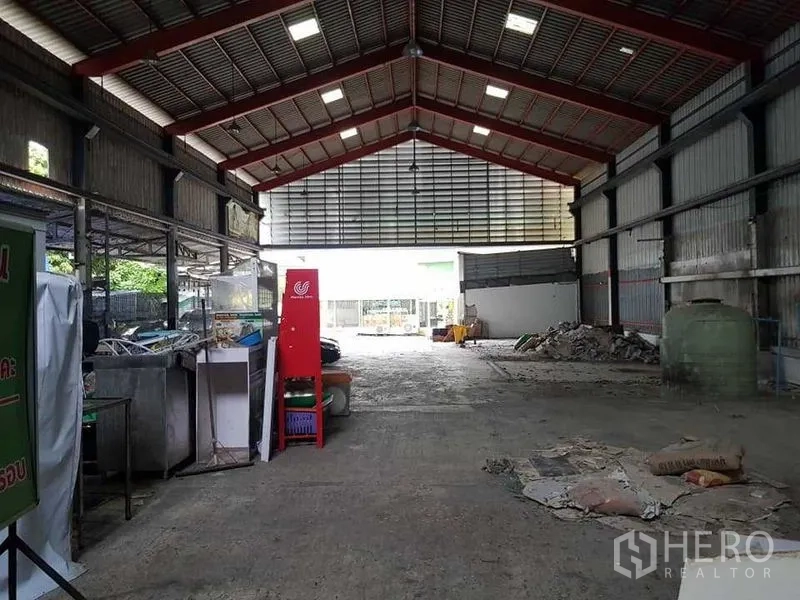 货栈 出租在Thung Khru, Bangkok - 仓库中央通道朝向大出入口，墙边放置设备与建材。