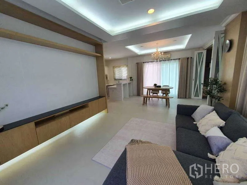 Detached House for rent in Saphan Sung, Bangkok - Living and dining space with feature TV wall, chandelier and sliding glass doors.