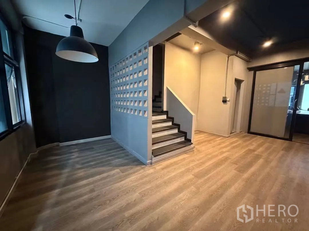 Home Office for rent in Watthana, Bangkok - Open area with wood flooring and central staircase beside a feature screen wall.