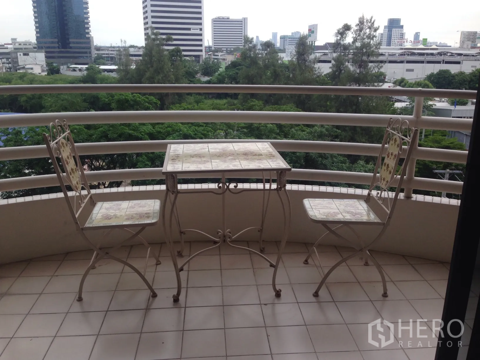 公寓 出租在Khlong Toei, Bangkok - 弧形阳台配茶几两椅，俯瞰绿地与曼谷天际线