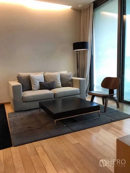 Condominium for rent in Watthana, Bangkok - Cozy lounge area with sofa, floor-to-ceiling glass and access to the balcony.