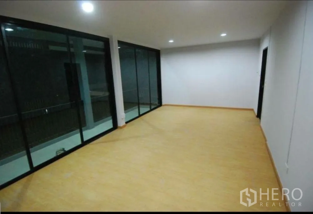 Home Office for rent in Lat Phrao, Bangkok - Long upper-level room with full-length glass wall and recessed ceiling lights.