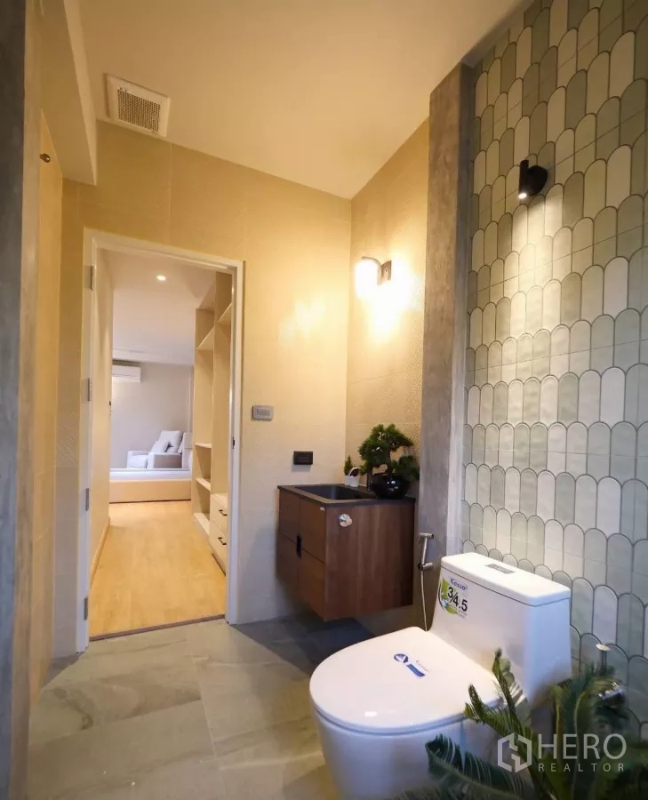 Townhouse for rent in Watthana, Bangkok - Bathroom with patterned wall tiles, wall-mounted vanity and toilet.