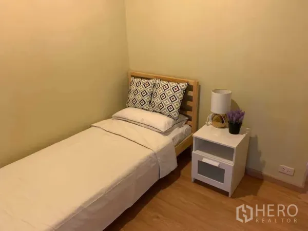 公寓 出租在Watthana, Bangkok - 次卧配单人床、白色床品与床头柜台灯，木地板。