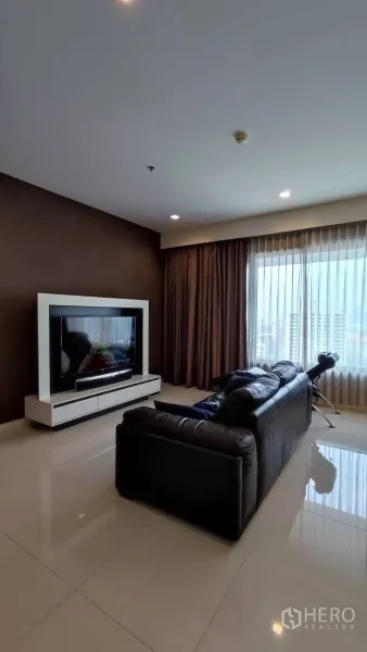 คอนโด ให้เช่าในSathon, Bangkok - ห้องนั่งเล่นมีโซฟาหนังดำหันเข้าหาชั้นวางทีวี หน้าต่างบานใหญ่พร้อมวิวเมืองและผ้าม่านโปร่ง
