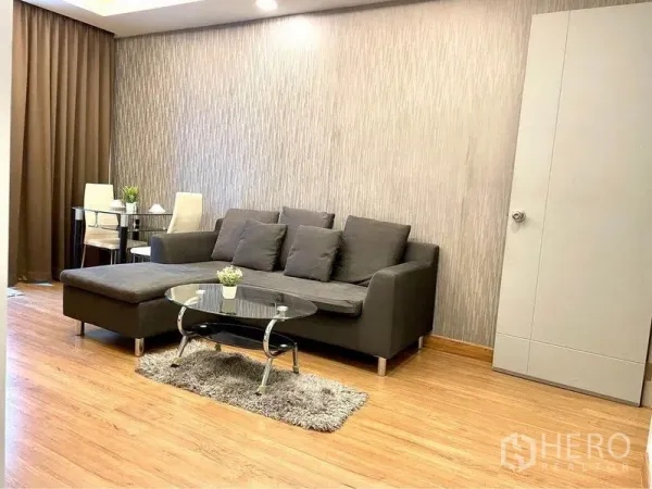 Condominium for rent in Huai Khwang, Bangkok - Cozy lounge area with gray sectional, glass coffee table and dining set.