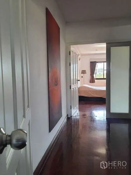 Townhouse for rent in Khlong Toei, Bangkok - Hallway with polished wood floors leading into a bright bedroom.