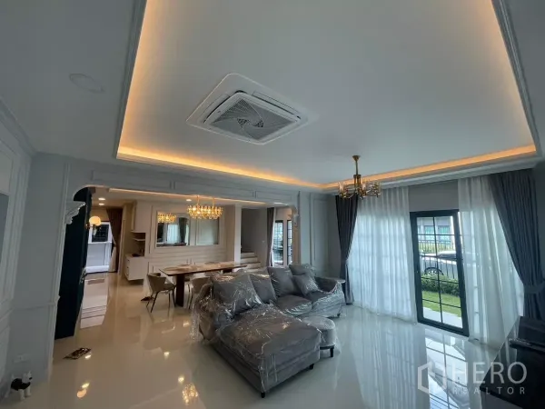 บ้าน ให้เช่าในBang Phli, Samut Prakan - ห้องนั่งเล่นสว่างเพดานซ่อนไฟ โซฟามุม และประตูกระจกสไลด์ออกสู่สวน