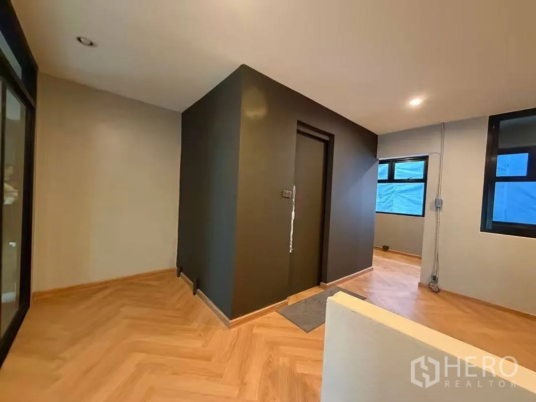 Home Office for rent in Watthana, Bangkok - Upper floor corridor with dark feature wall and multiple windows.