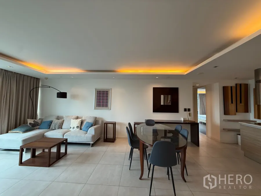 公寓 出租在Phaya Thai, Bangkok - 开放式客餐厅，吊顶氛围灯，转角沙发与玻璃餐桌。
