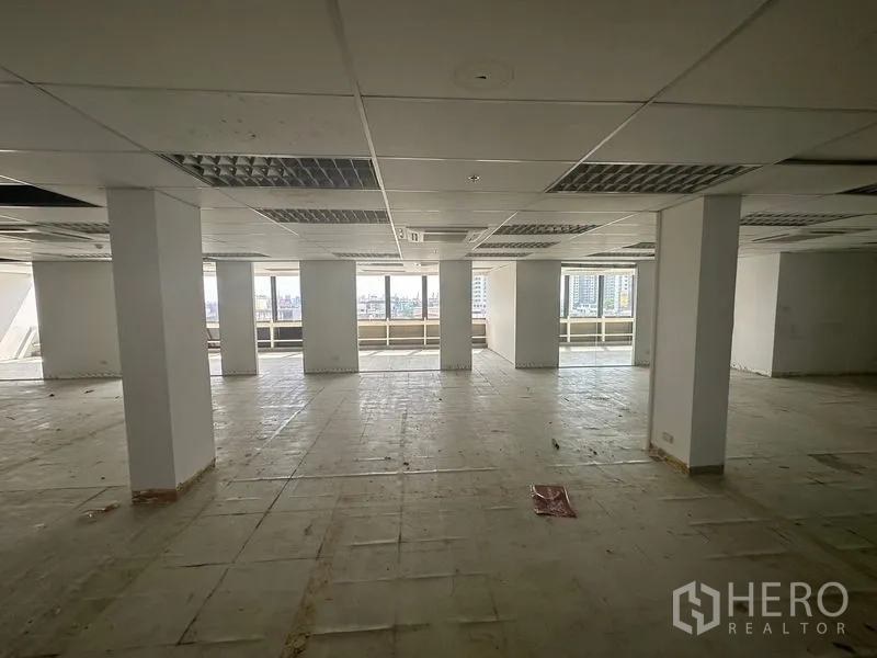 办公空间 出租在Khlong Toei, Bangkok - 开放式办公楼层，带立柱、吊顶与整排窗户，可眺望曼谷天际线。