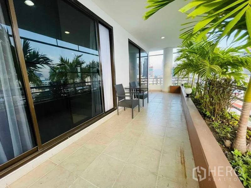 Condominium for rent - Spacious covered balcony with potted palms, city skyline views, and sliding glass doors.