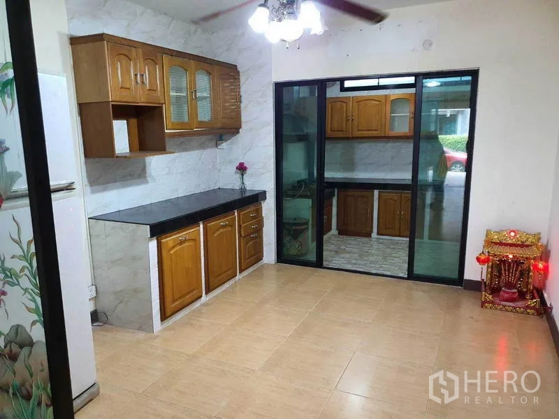 Townhouse for sale in Khlong Toei, Bangkok - Dining area with built-in cabinetry and sliding glass doors to a secondary kitchen.