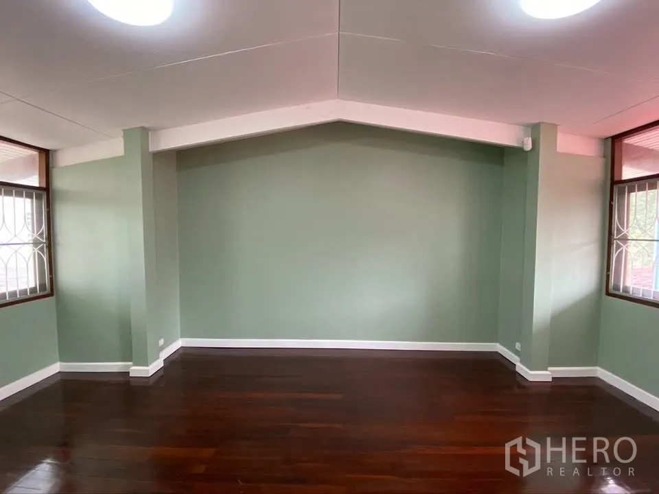 Detached House for rent in Suan Luang, Bangkok - Symmetrical green-walled room with dark wooden flooring.