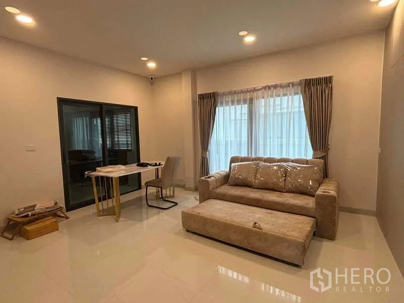 独立式住宅 出租在Mueang Nonthaburi, Nonthaburi - 温馨客厅，沙发、小餐桌与落地窗帘。
