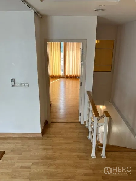 联排别墅 出租在Wang Thonglang, Bangkok - 二层过道，木质楼梯与通向明亮房间的门