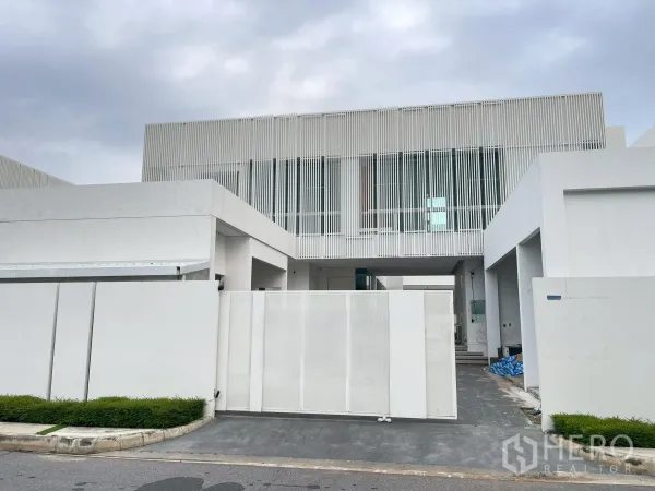 独立式住宅 出售在Bang Phli, Samut Prakan - 现代两层白色立面，竖向百叶与滑动大门。