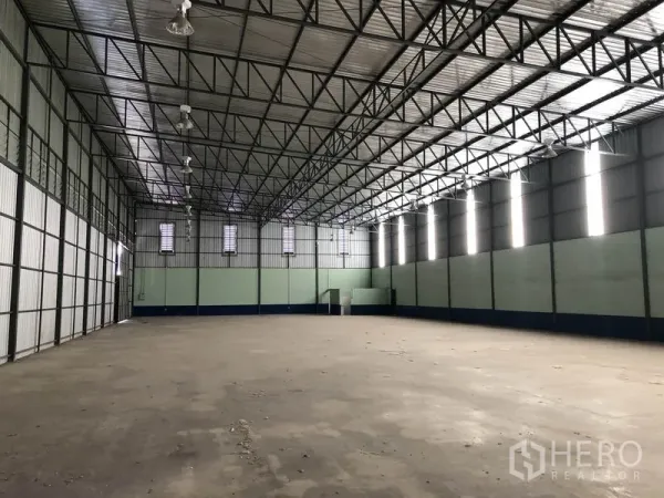 Warehouse for rent in Pathum Thani - Spacious warehouse interior showing a high steel‑truss roof and open concrete floor.