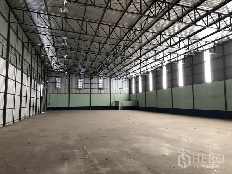 Warehouse for rent in Pathum Thani - Spacious warehouse interior showing a high steel‑truss roof and open concrete floor.
