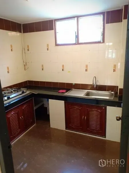 Townhouse for rent in Phra Khanong, Bangkok - Windowed Thai kitchen with tiled walls, long countertop, sink and gas hob.