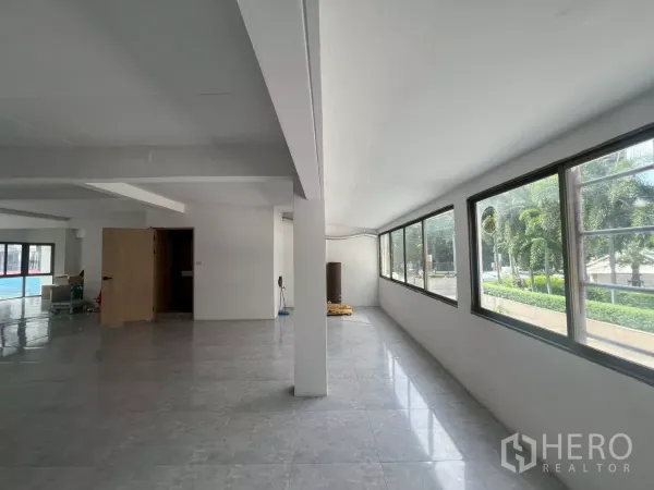 Retail Space for rent in Pathum Wan, Bangkok - Sunlit corridor with a row of windows overlooking palm trees and landscaping.