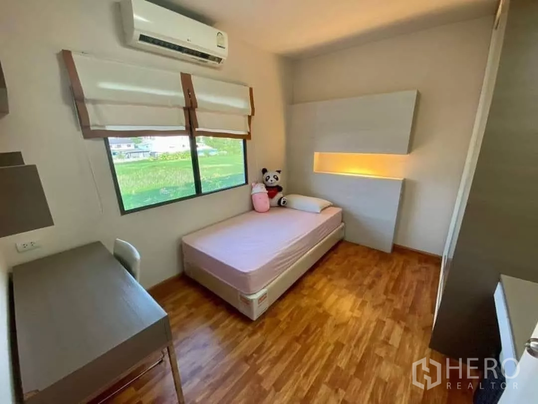 Townhouse for rent in Khlong Toei, Bangkok - Bright single bedroom with study desk, large window, air conditioner and wood flooring.