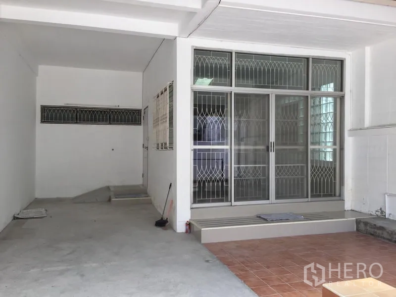 联排别墅 出租在Phra Khanong, Bangkok - 带顶棚的前院车位，防盗滑门与瓷砖入户平台。