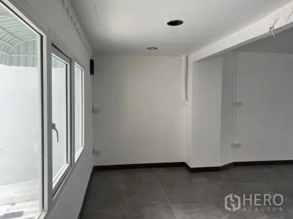 Retail Space for rent in Khlong Toei, Bangkok - Bright retail corner with large windows, white walls and grey tiled floor.
