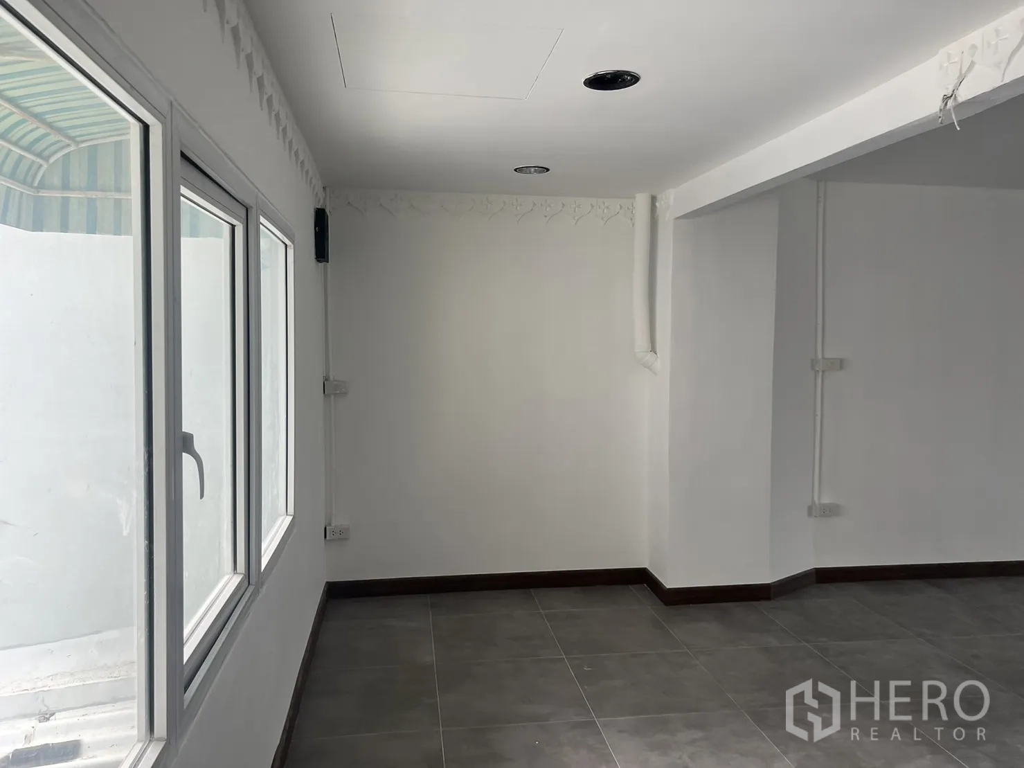 Retail Space for rent in Khlong Toei, Bangkok - Bright retail corner with large windows, white walls and grey tiled floor.