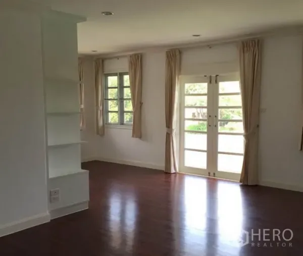 Detached House for rent in Bang Phli, Samut Prakan - Bright living room with hardwood floors, French doors, and curtained windows.
