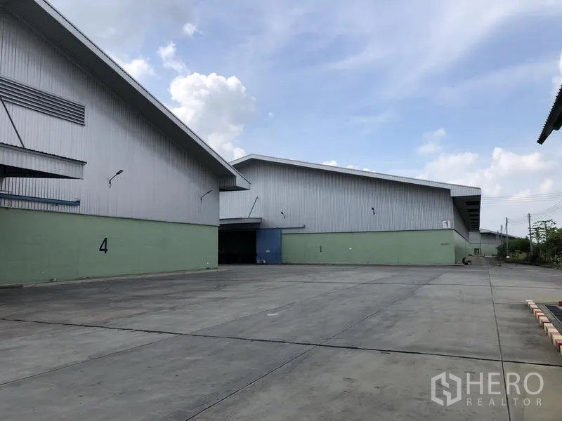 Warehouse for rent in Phra Nakhon Si Ayutthaya - Wide concrete circulation yard between numbered warehouse buildings for truck maneuvering.